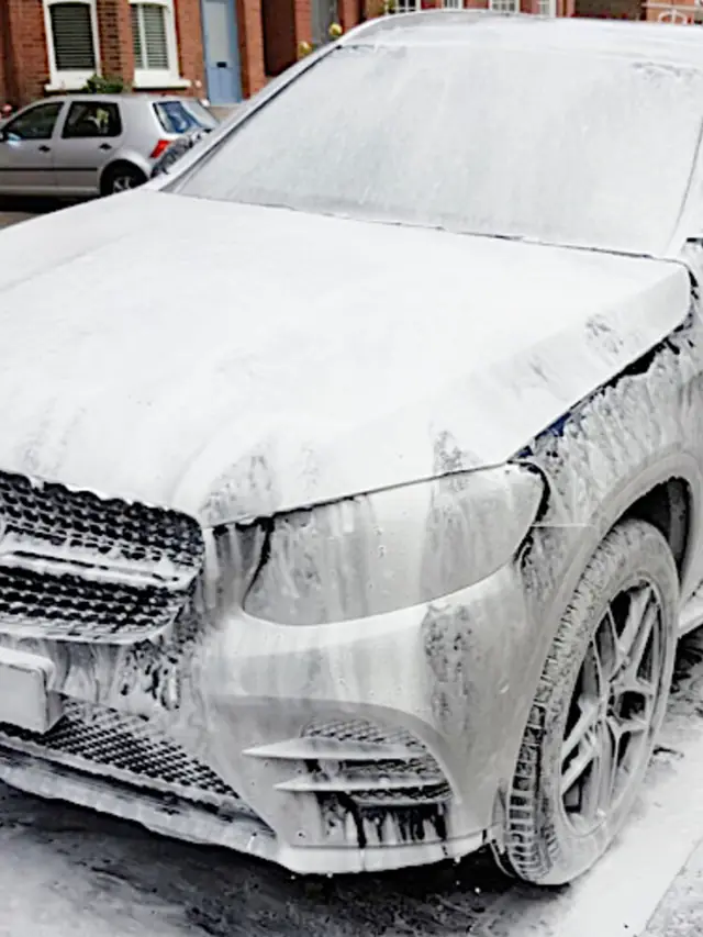A Mercedes SUV covered in snow foam outside a brick terrace in Greenwich