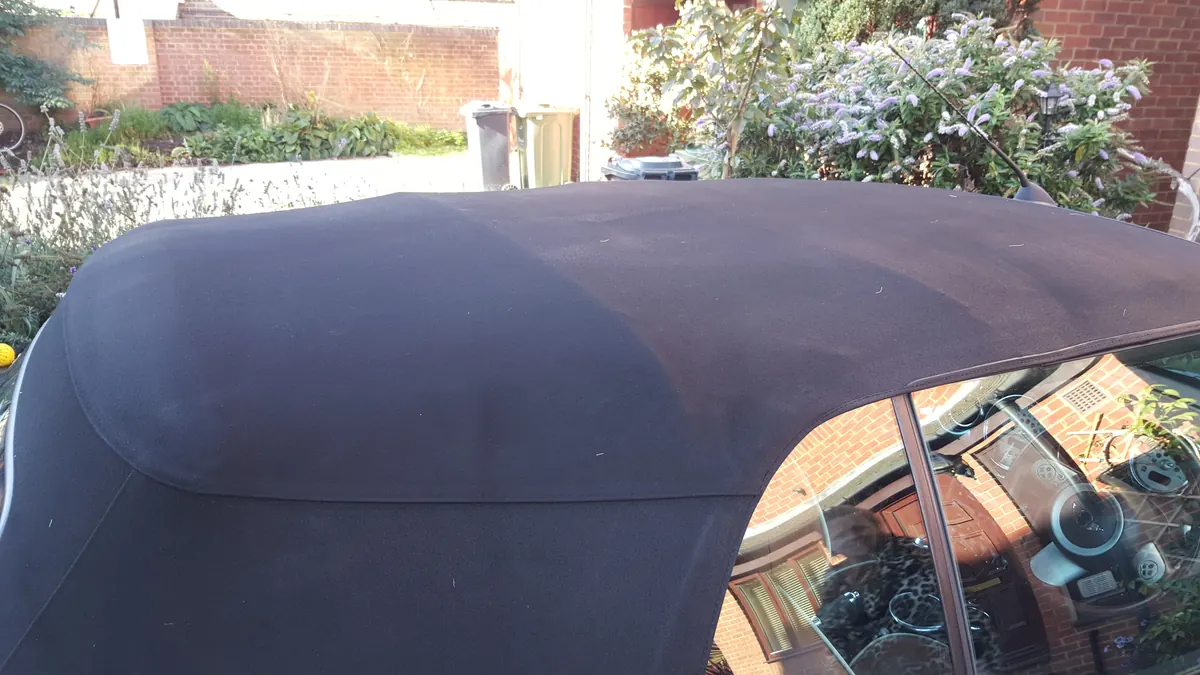 A fabric soft top cleaned to an even black